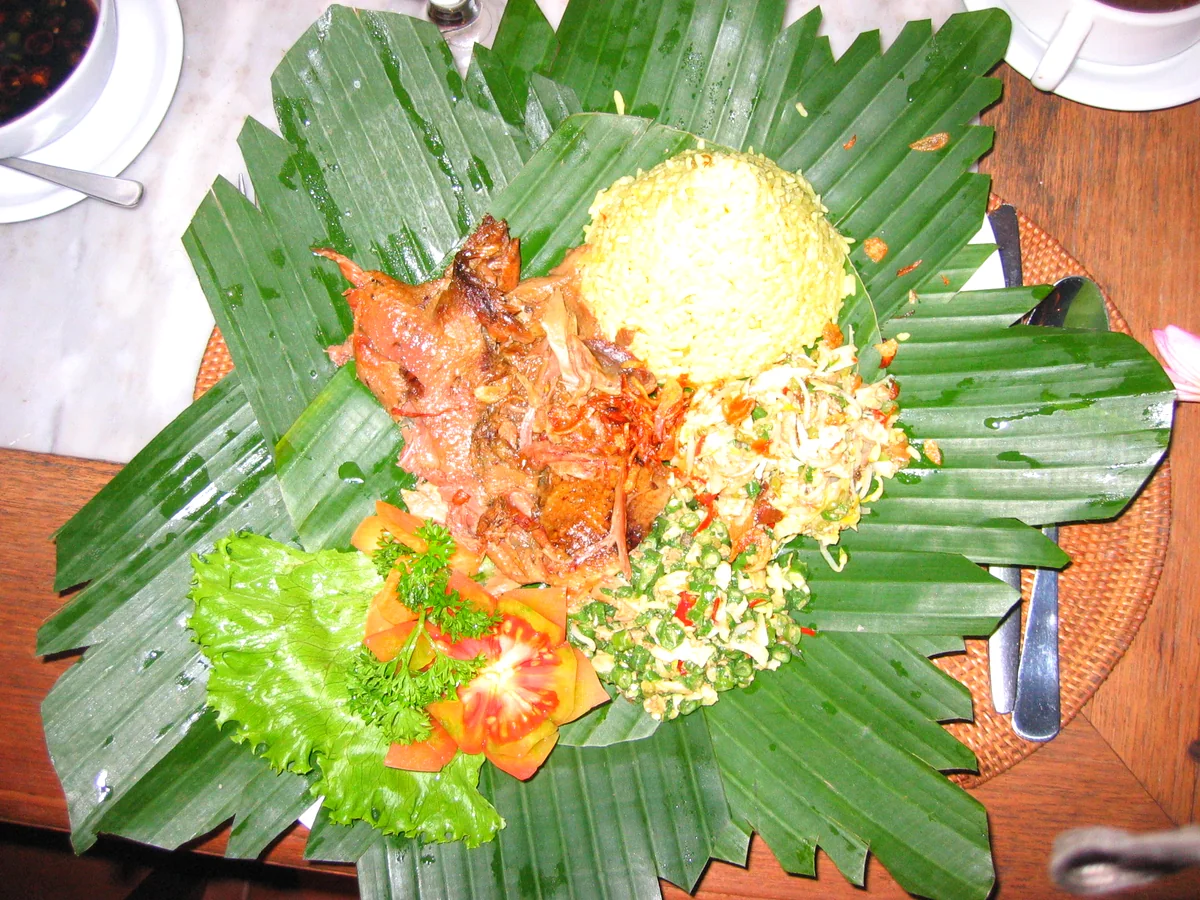 Betutu servi sur une feuille de banane, avec riz safrané, légumes et sauce