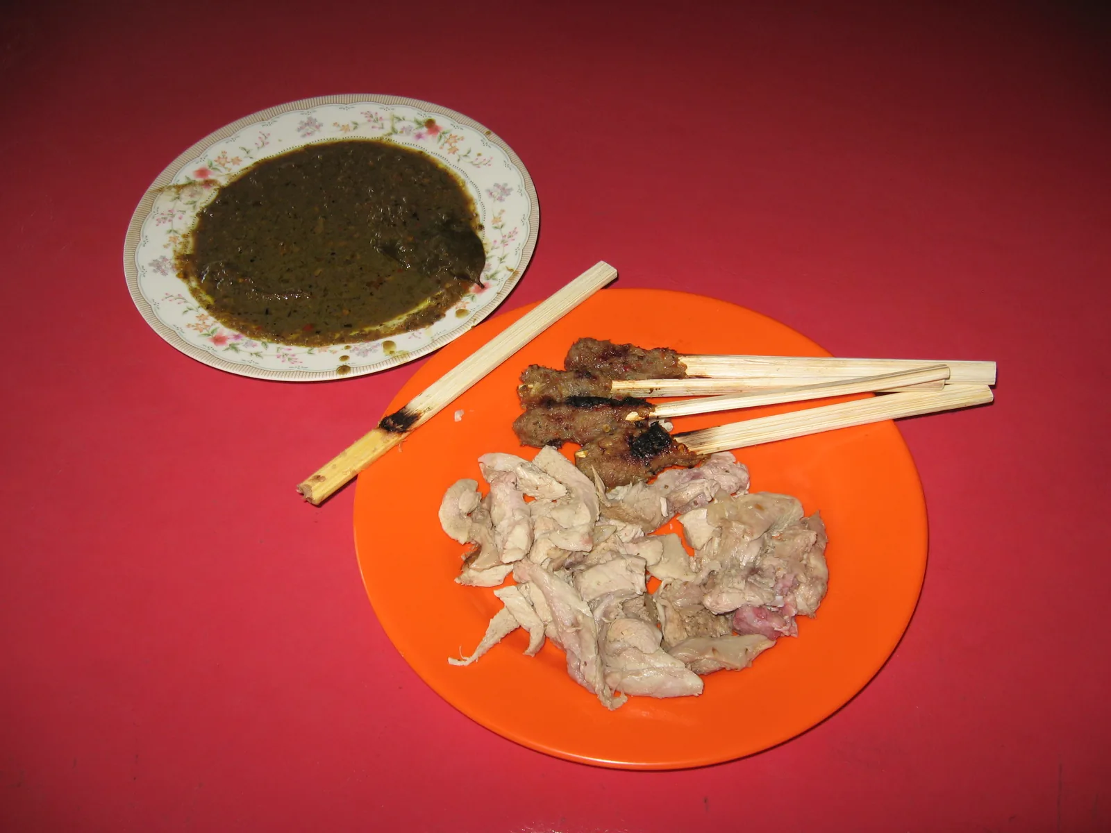 Assiette de babi guling avec des brochettes de sate lilit et un bol de sauce
