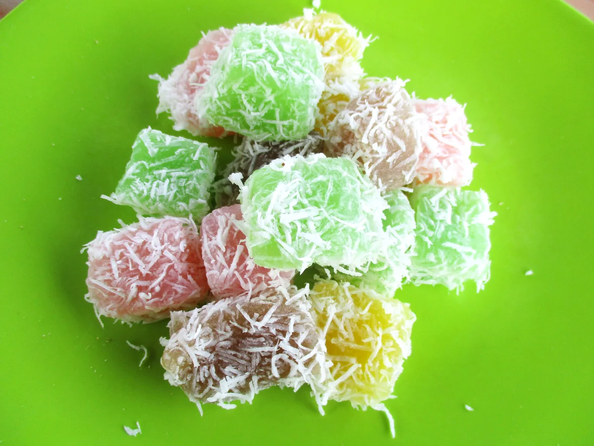 Petits gâteaux balinais colorés roulés dans la noix de coco râpée, sur une assiette