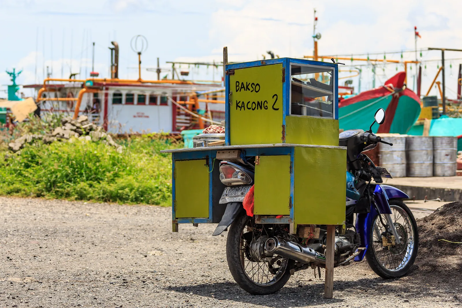 Moto équipée d’une petite cuisine vitrée de vendeur de bakso, garée sur le port de Benoa